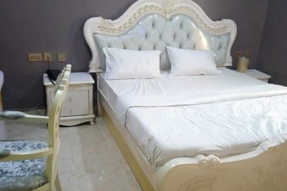 Un dormitorio con una cama grande, una mesita de noche, una silla y un aparador.