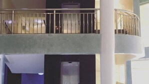 A multi-level interior with a central elevator, a balcony with metal railings, and a marble floor. - Gold Crown Hotel (Owerri)