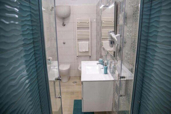 A modern bathroom with a glass shower enclosure, a white sink, and a toilet. - Gleda Rooms (Pompei)