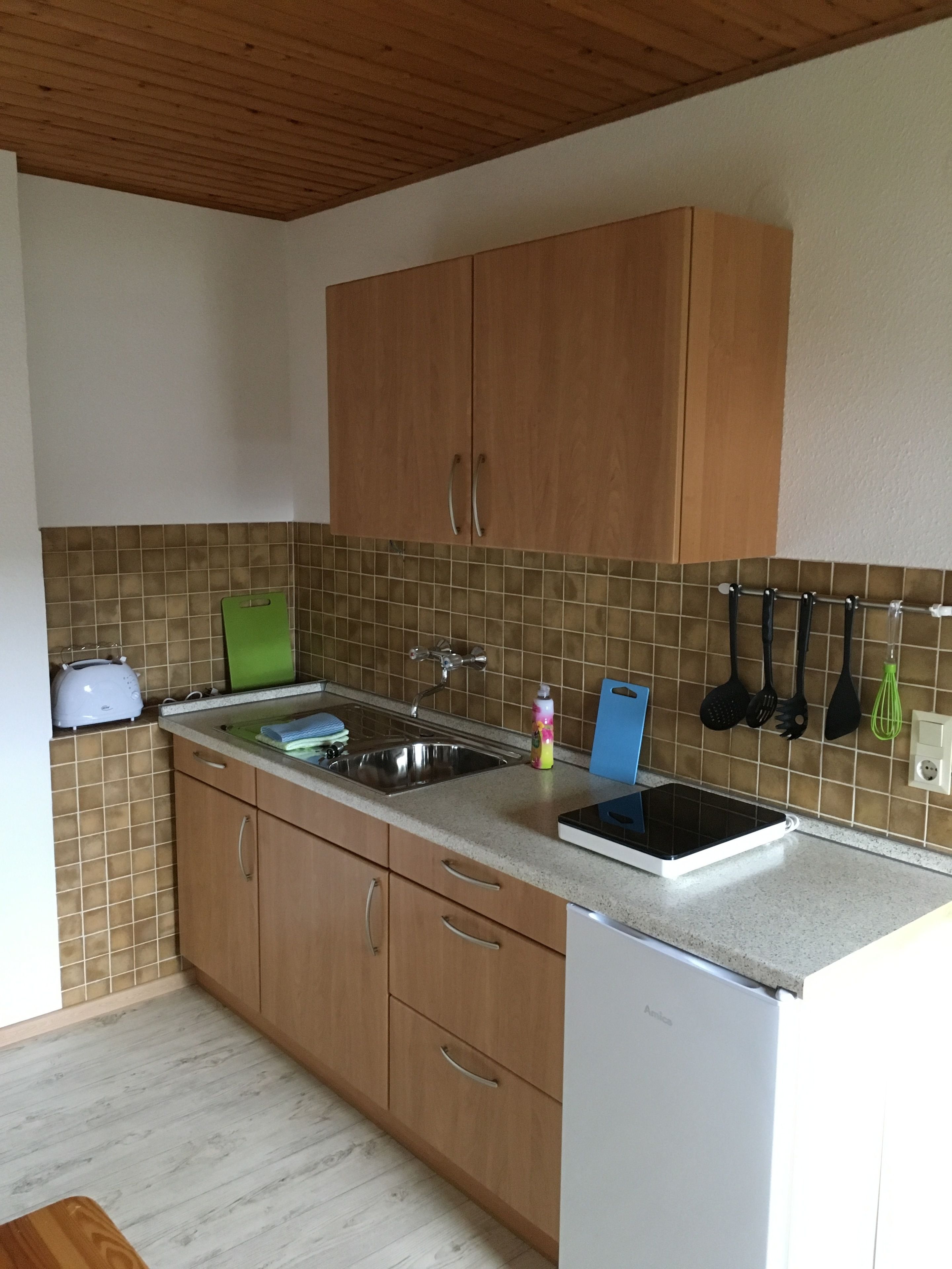 A kitchen with wooden cabinets, a stainless steel sink, a toaster, and a white dishwasher.