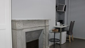 Una camera moderna con camino in marmo, un tavolino con una ciotola, una sedia e una TV a parete.