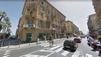 A street view with buildings, a crosswalk, and parked cars.