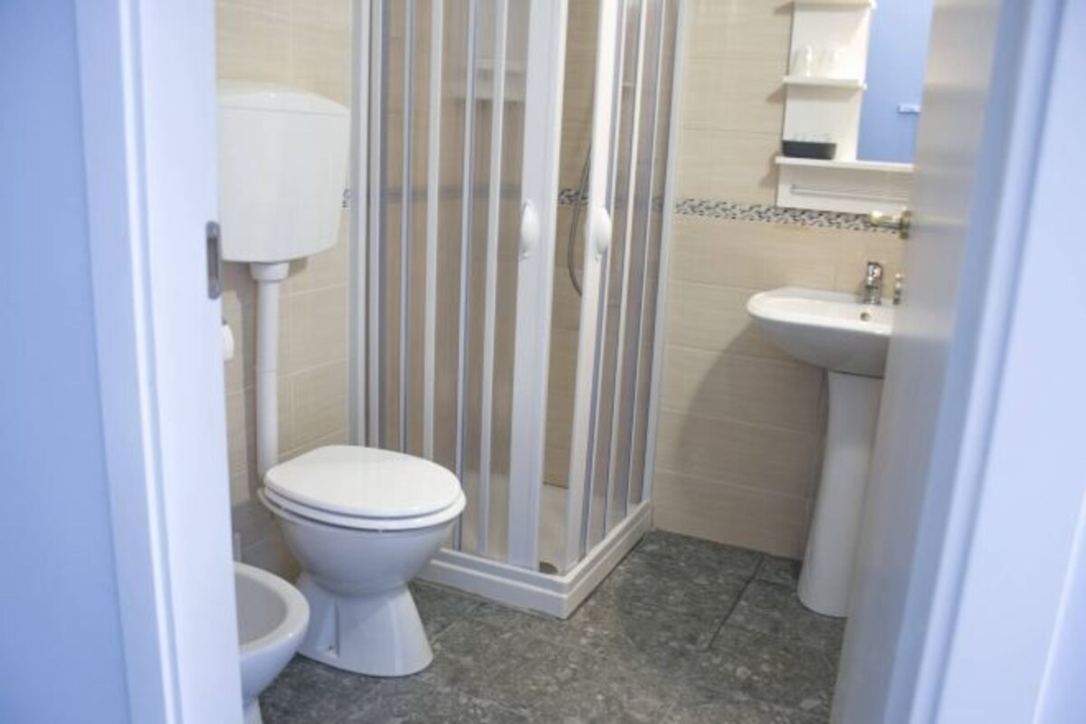 A bathroom with a toilet, shower enclosure, and sink.