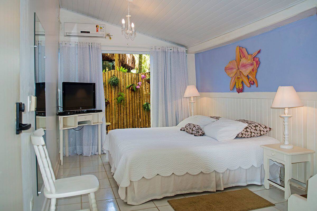 A bedroom with a bed, a TV, a desk, and a chair.