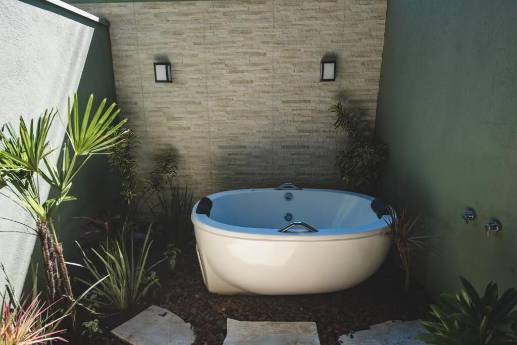 Uma área de spa com hidromassagem, rodeada por plantas e uma parede de pedra.