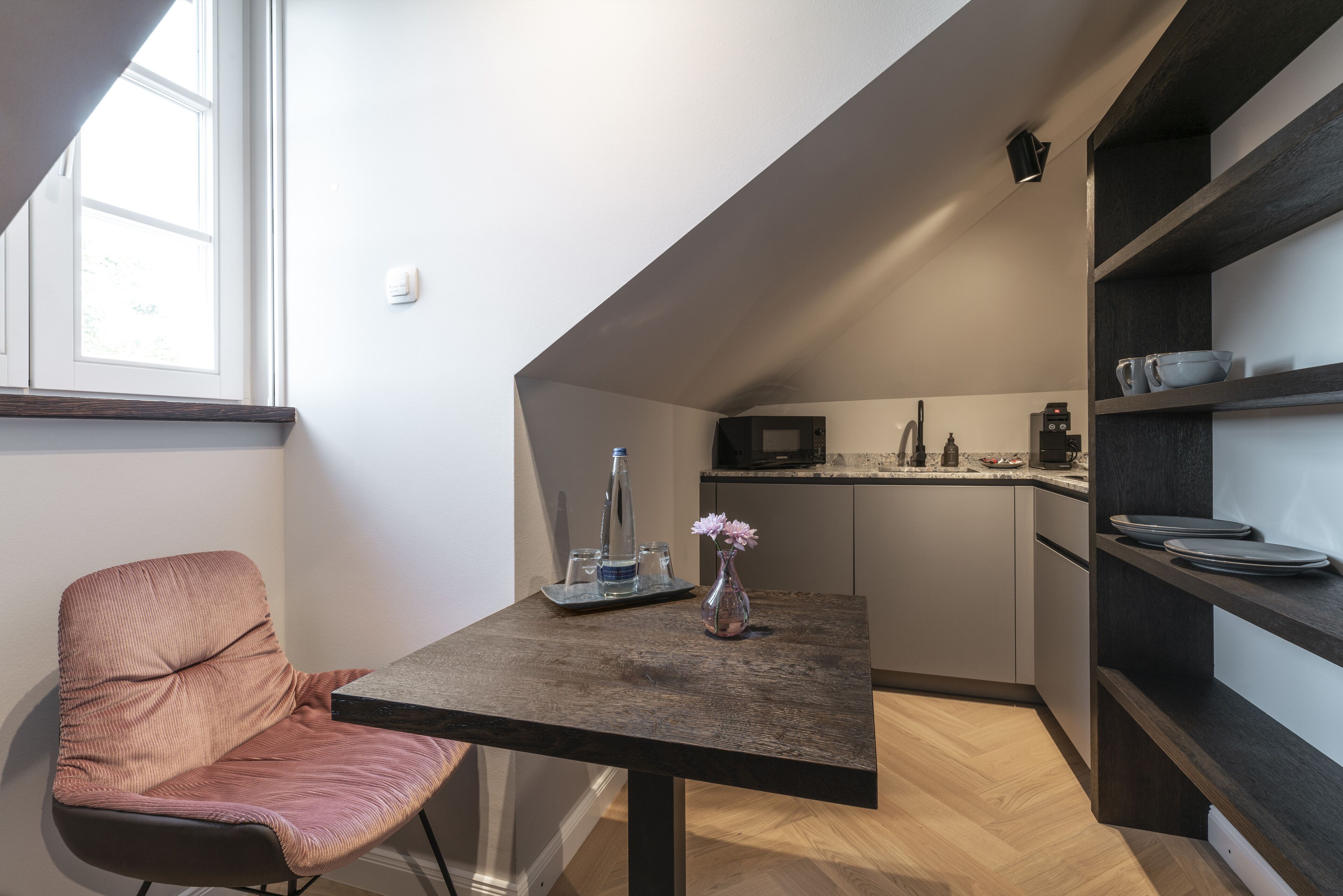 Una cocina compacta con comedor, que incluye una mesa, una silla y un pequeño jarrón con flores.