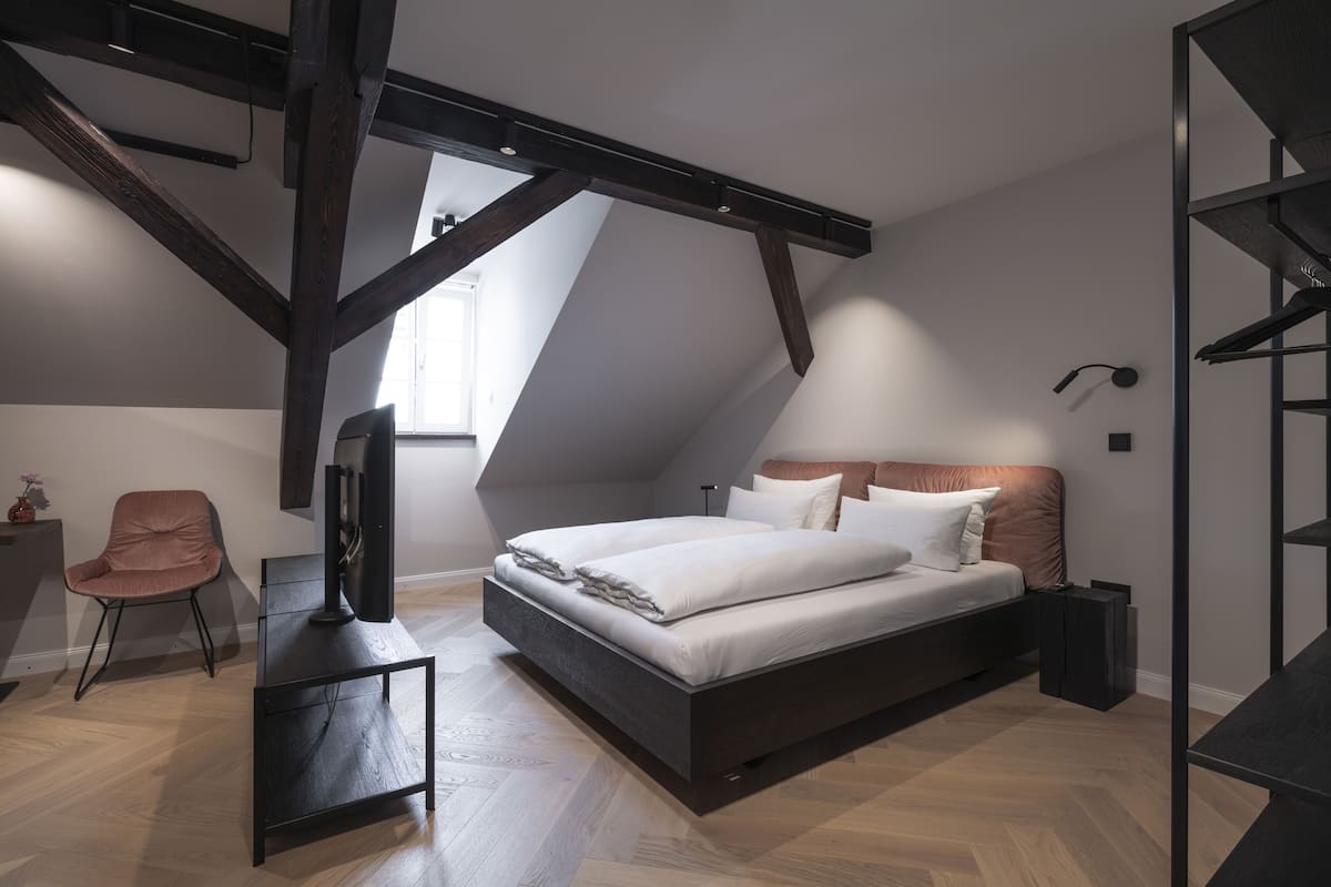 A modern bedroom with a loft-style bed, a desk, and a chair.