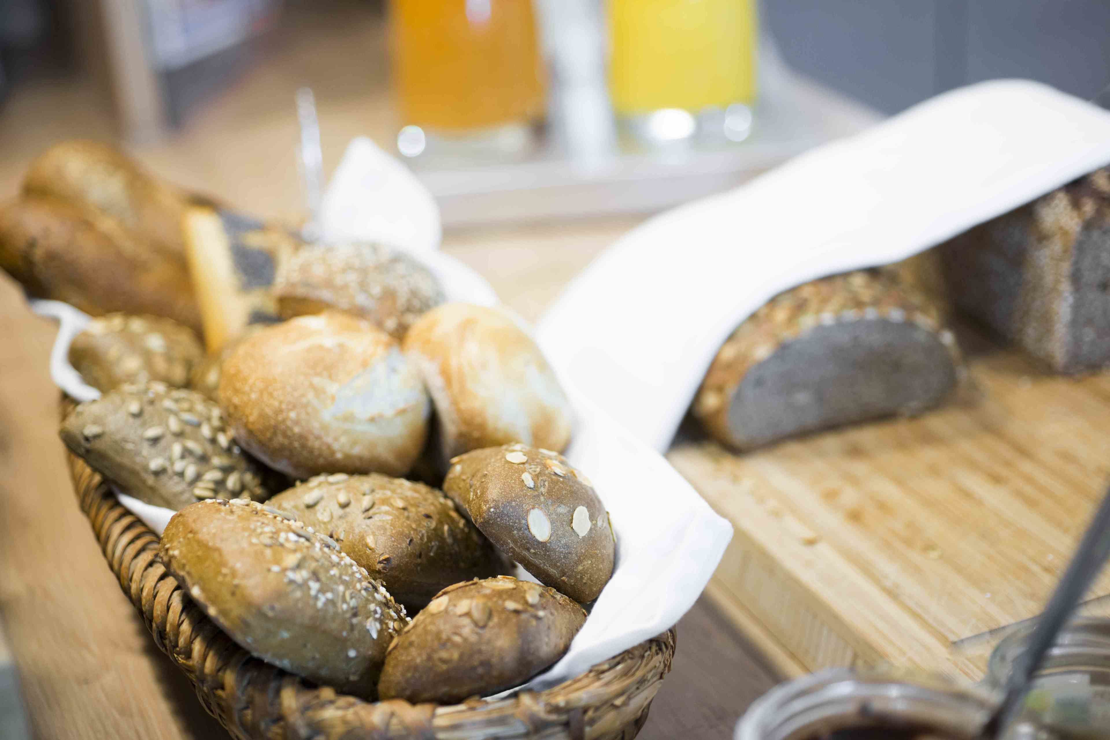 A basket of various breads on a wooden table.