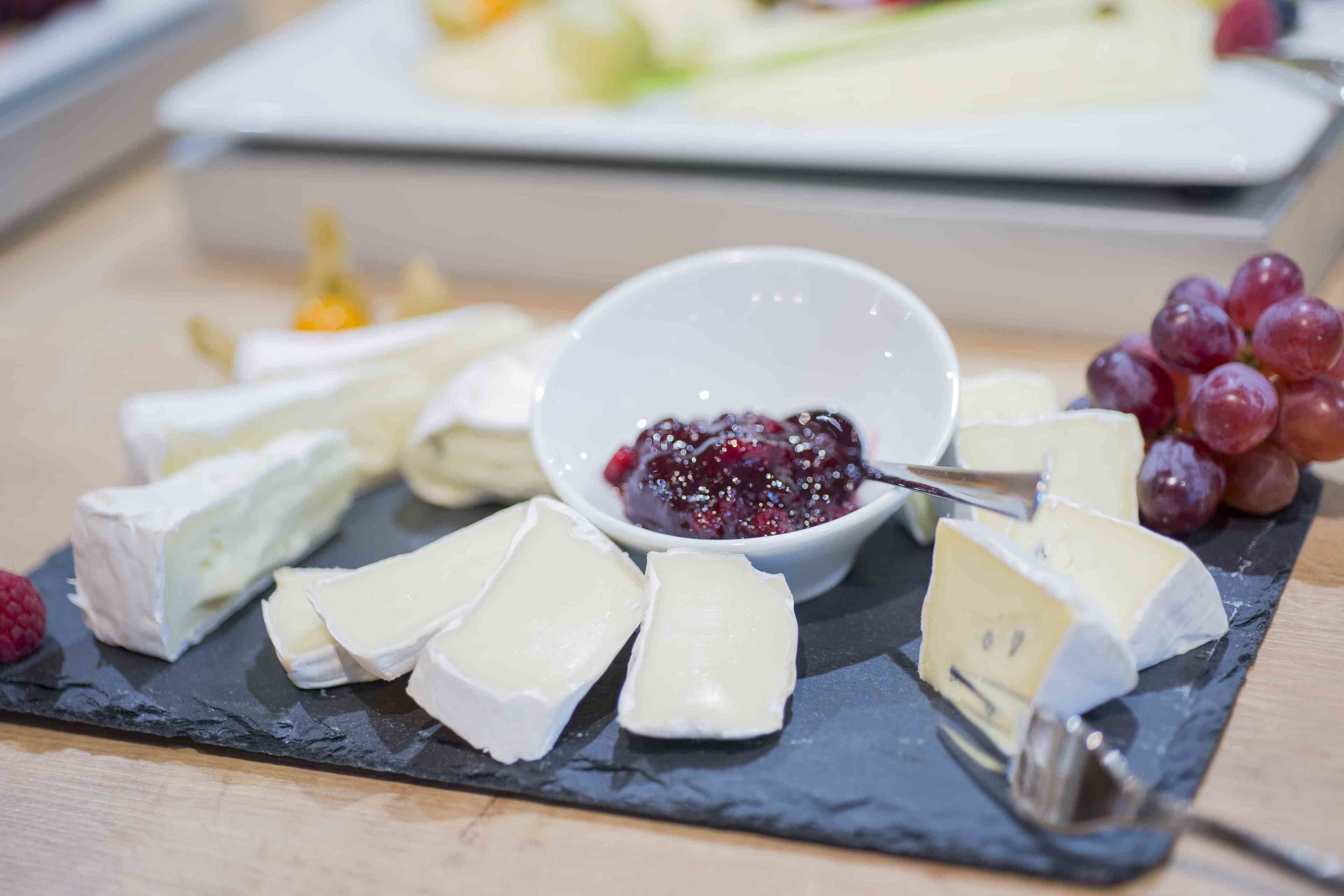 A variety of cheeses and grapes on a slate board.