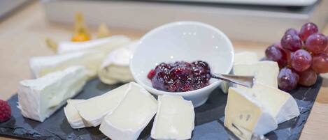 A variety of cheeses and grapes on a slate board.