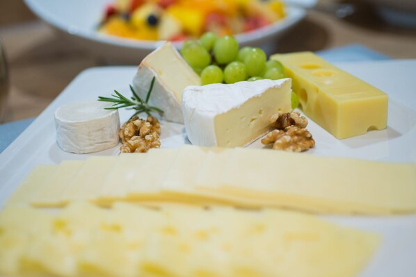 A variety of cheeses and fruits on a white plate.