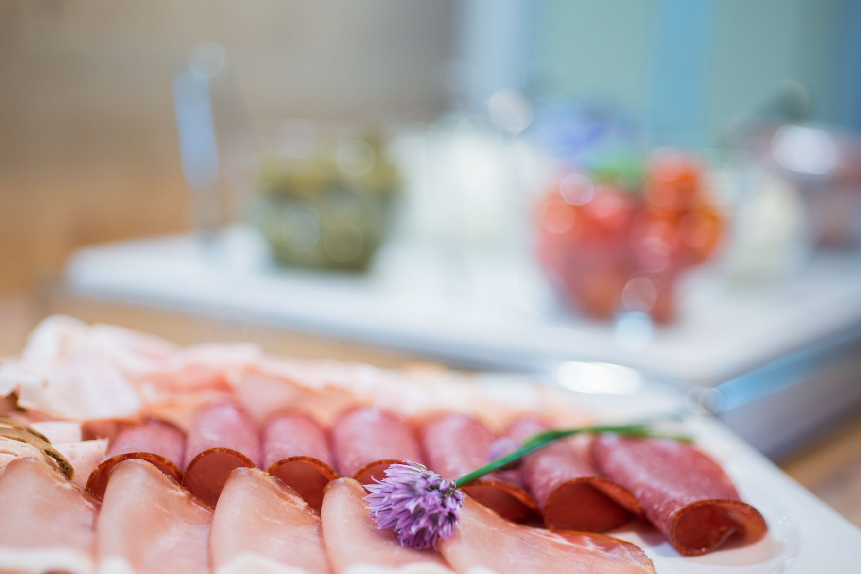 A platter of sliced meats with a flower garnish.