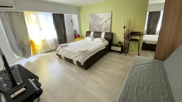 Une chambre d’hôtel moderne avec un grand lit, un bureau avec un ordinateur portable et une vue sur l’extérieur.