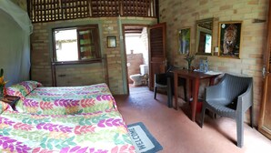A room with two beds, a desk with a chair, a mirror, and a door leading to a bathroom. - Atta Rainforest Lodge (Mauisparu)
