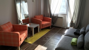 A living room with two orange armchairs, a grey sofa, a small table, and a floor lamp. - New Central Roof Top (Bucharest)