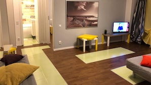 A modern living room with a wooden floor, a sofa, a yellow table, and a TV. - New Central Roof Top (Bucharest)