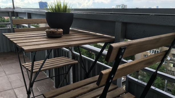 A balcony with a wooden table and chairs, a potted plant, and a small decorative item. - New Central Roof Top (Bucharest)