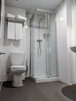 Un baño moderno con ducha de vidrio, inodoro y lavamanos.