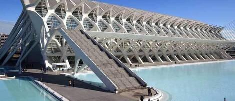 A modern architectural building with a unique roof design and a large pool area.