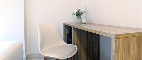 A modern room with a white chair, a wooden desk, and a small plant on the desk.