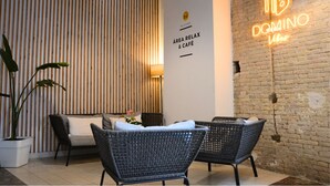 A modern interior with wicker furniture, a neon sign, and a vertical wooden panel wall. - Original Domino House Hotel (Valencia)