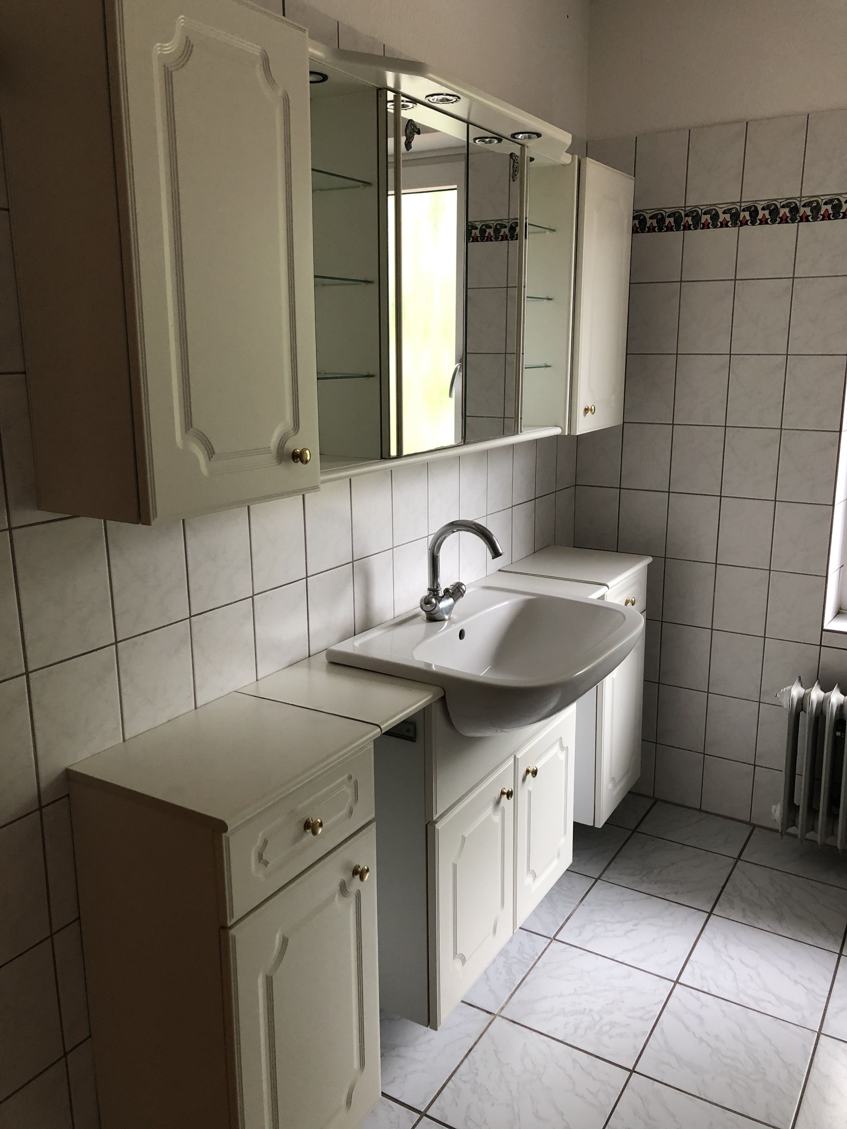 Une salle de bain avec un lavabo blanc, un miroir et un meuble.