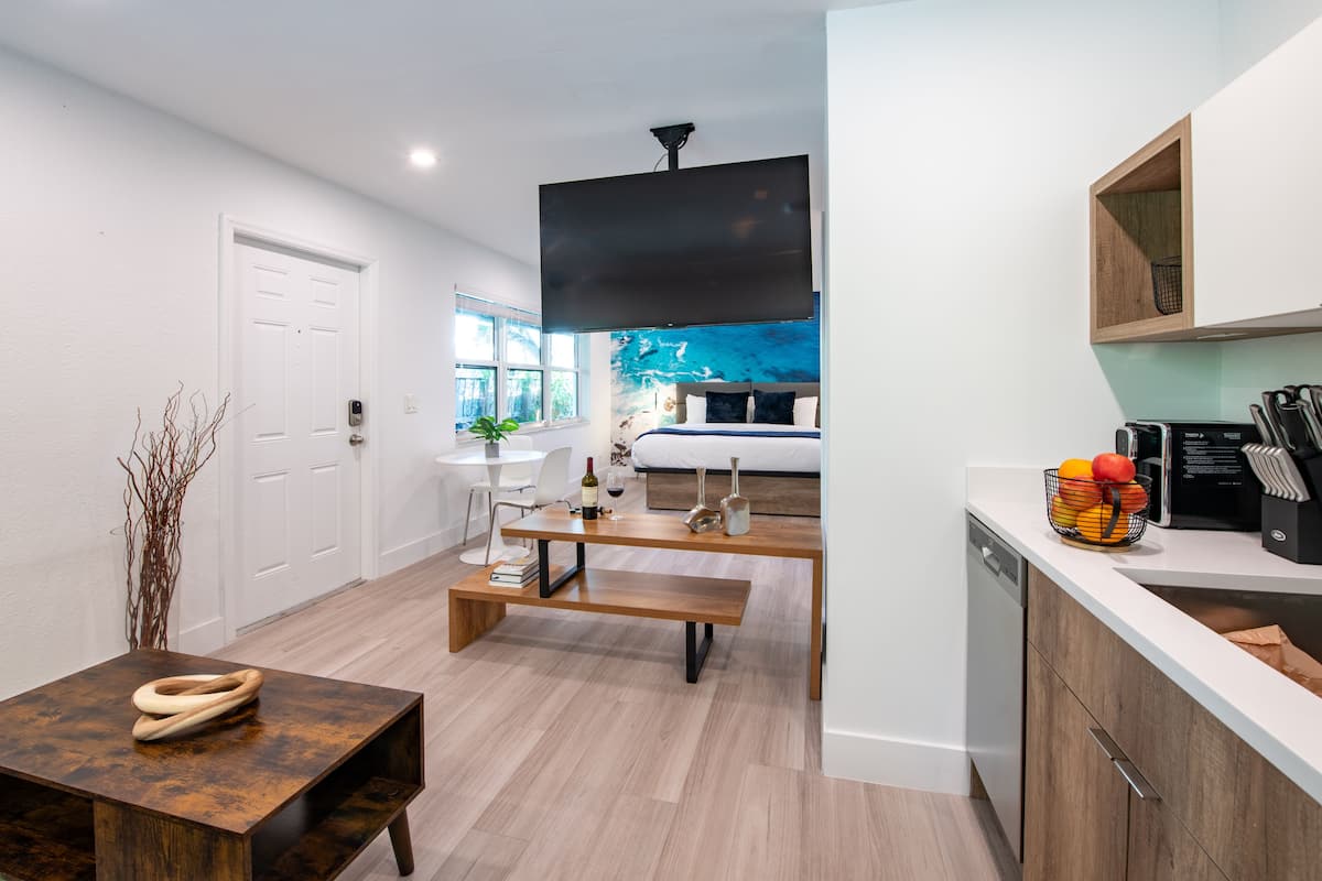 Una cocina moderna con lavavajillas, un banco de madera y una mesa de comedor con un florero y libros.