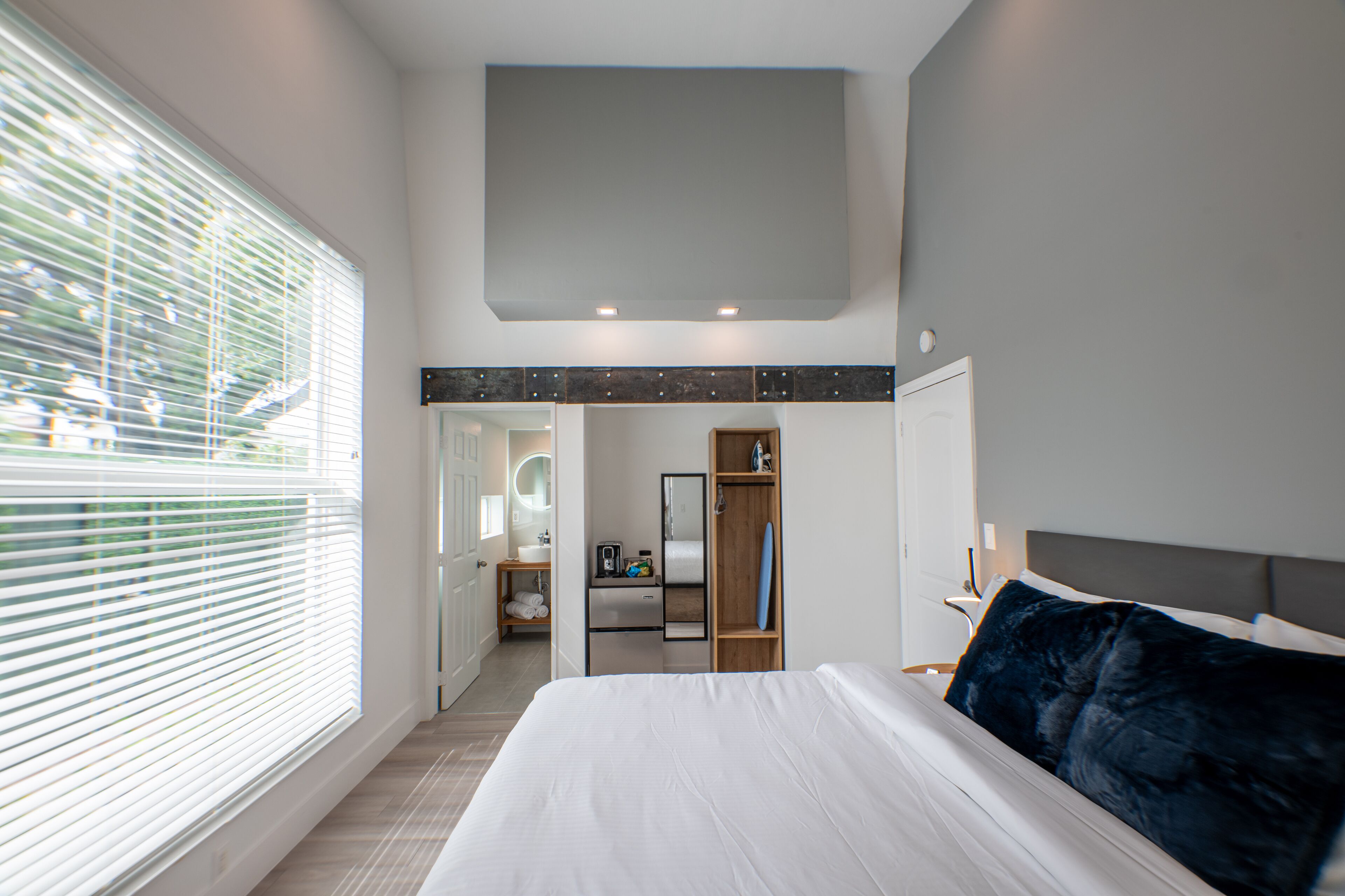 Ein modernes Schlafzimmer mit einem großen Bett, einem begehbaren Kleiderschrank und einem durchgehenden Türrahmen einsehbarer Badezimmer.