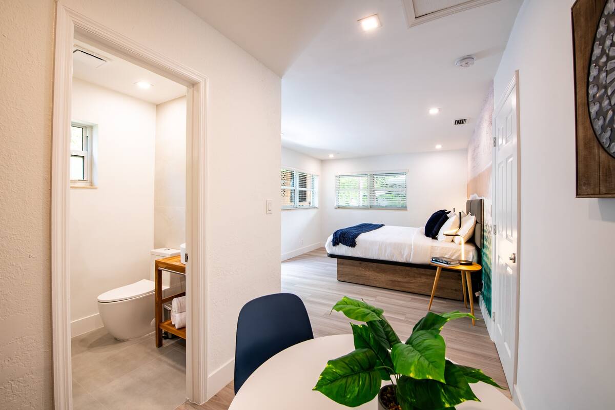 Un dormitorio moderno y funcional con cama, mesita de noche y vistas a un balcón.