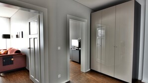 Een moderne hotelkamer met een houten vloer, een ruime inloopkast en een bed met een rode hoofdeinde.