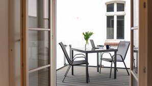 Een open balkon met een tafel en stoelen, een laptop, en een bloevas.