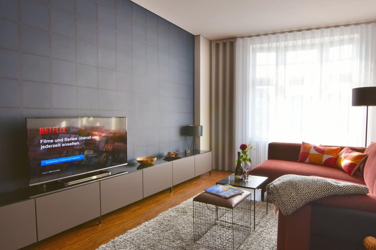 Una sala de estar moderna con televisor de pantalla plana, un sofá, una mesa de centro y una lámpara.