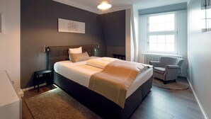 Een moderne slaapkamer met een groot bed, een nachtkastje, een stoel en een raam.
