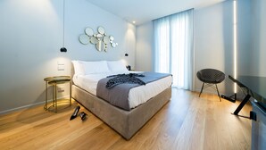 Ein modernes Schlafzimmer mit einem Bett, Nachttischen, einem wandmontierten Spiegel und einem Sessel.