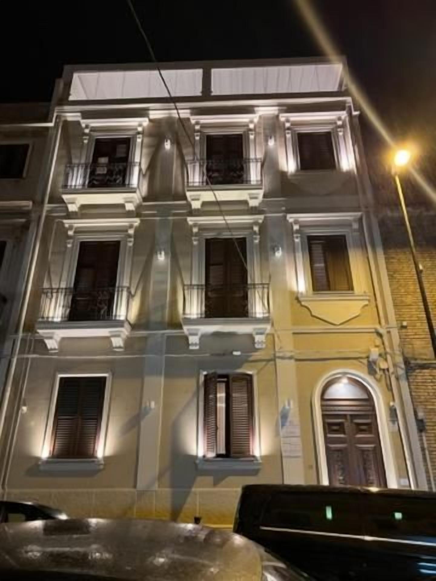 Un edificio a più piani con balconi e finestre, illuminato da luci stradali.