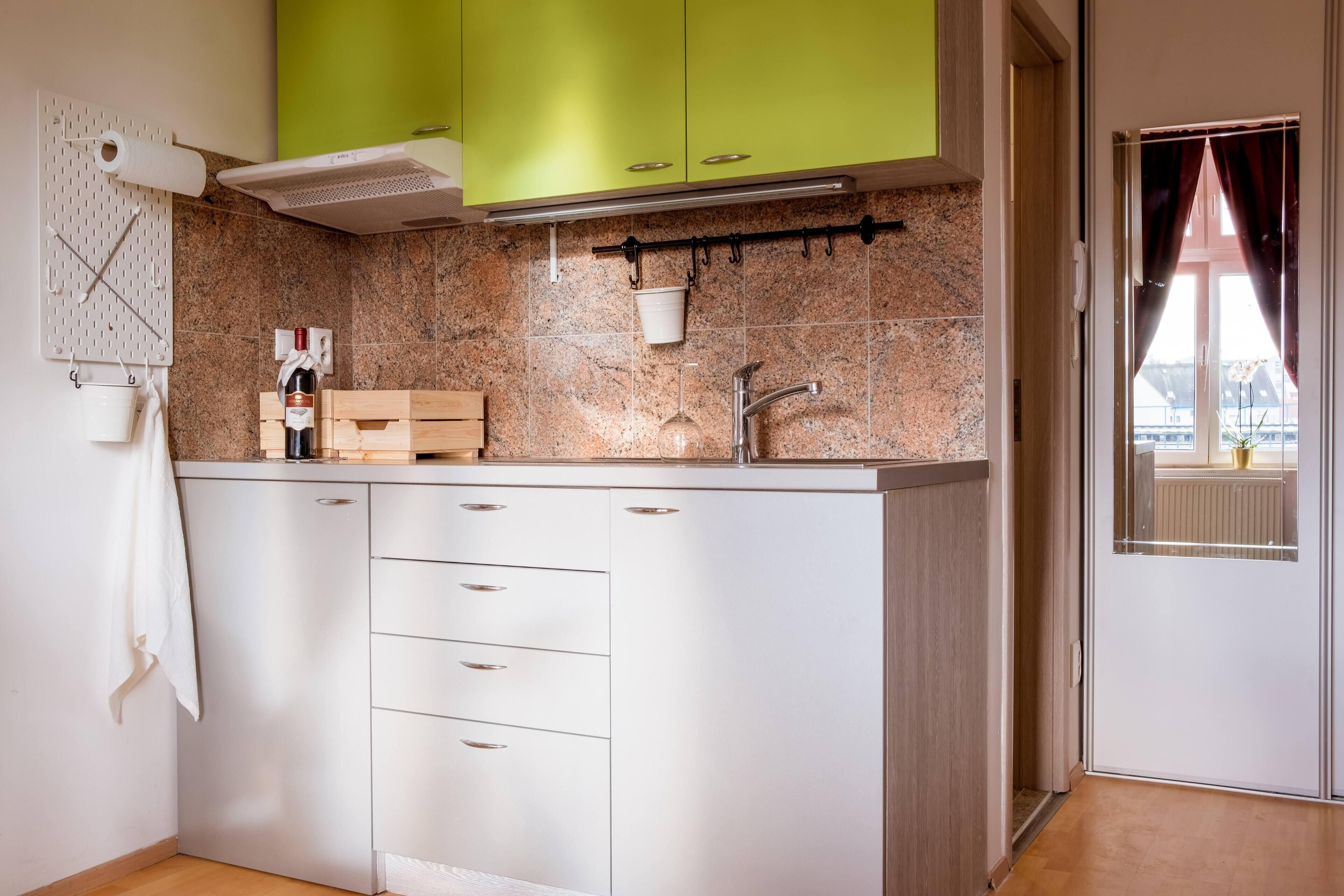 Eine moderne Küche mit weißen Schränken, einer Arbeitsplatte aus Granit und einer hängenden Pfannenleiste.