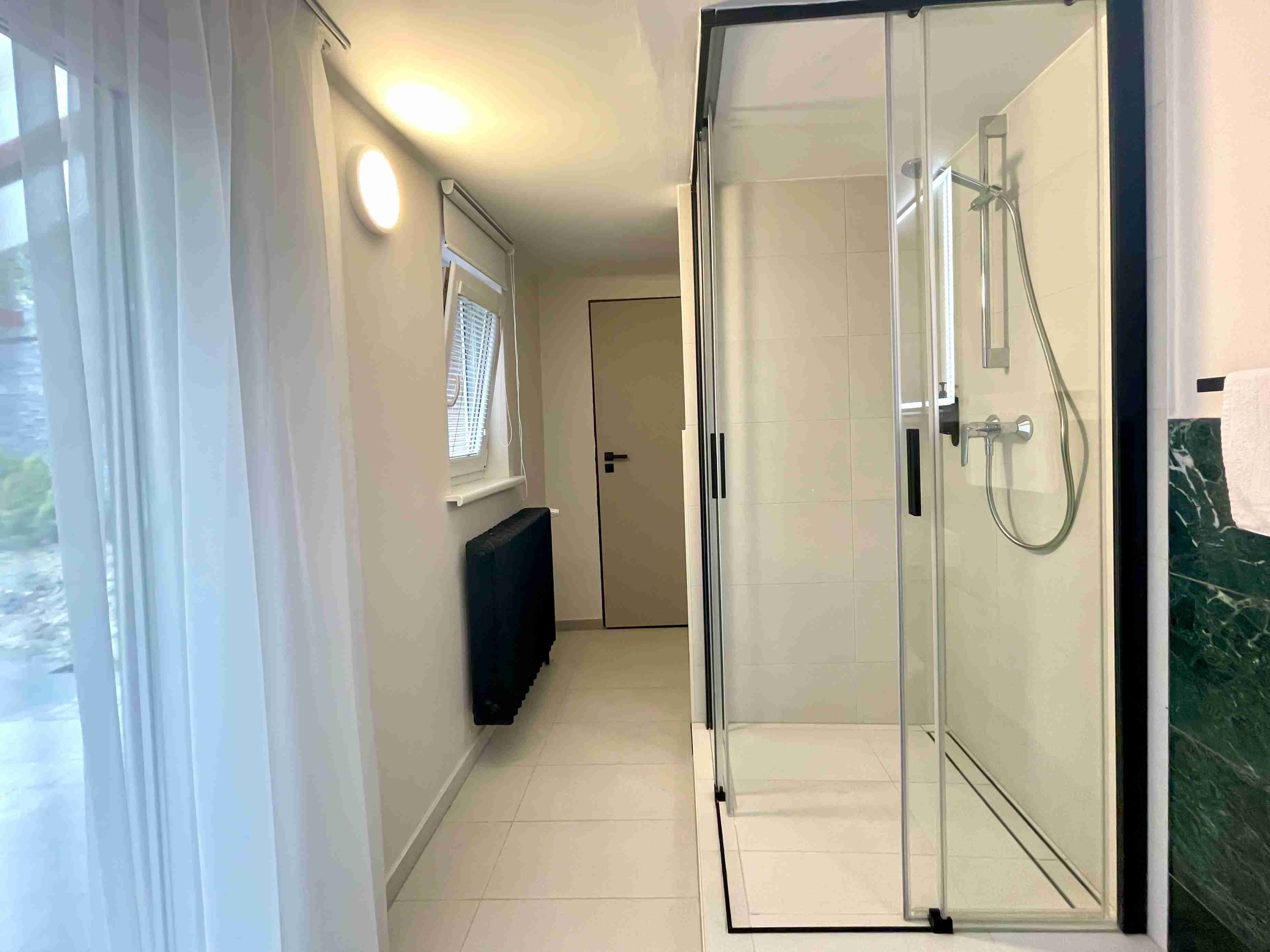 Een moderne badkamer met een douchecabine van glas, een toilet en een wastafel.