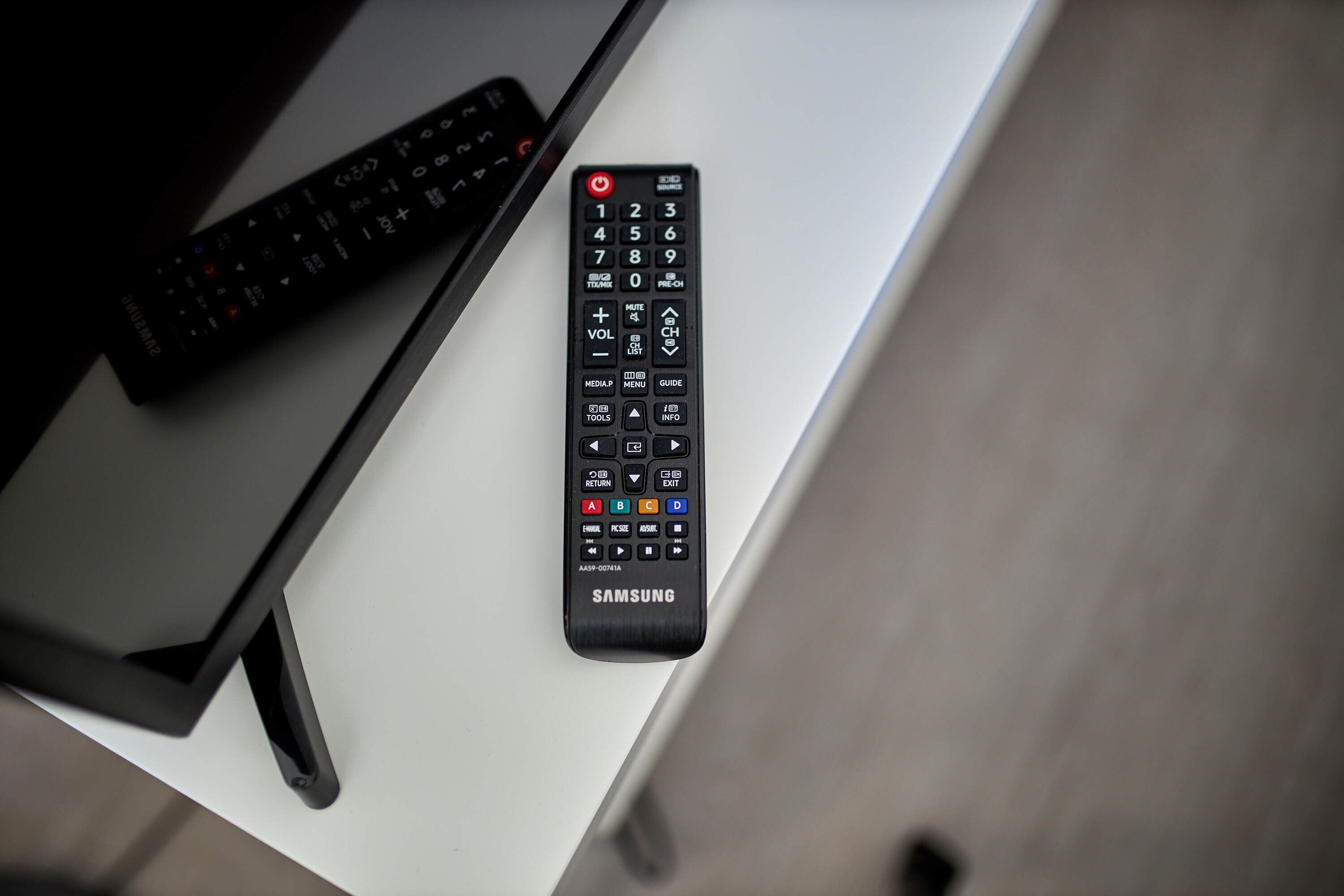 Two remote controls on a white table.