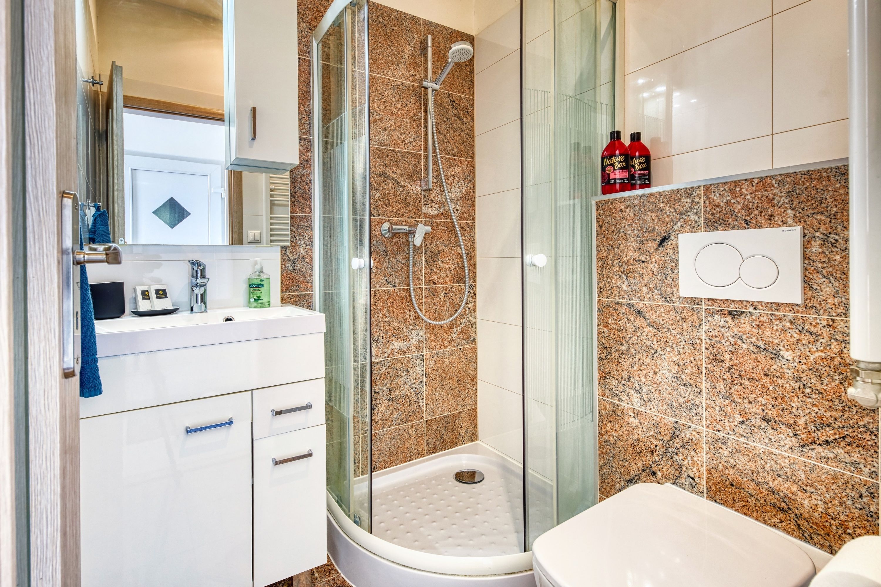 A modern bathroom with a glass-enclosed shower, a white sink, and a toilet.