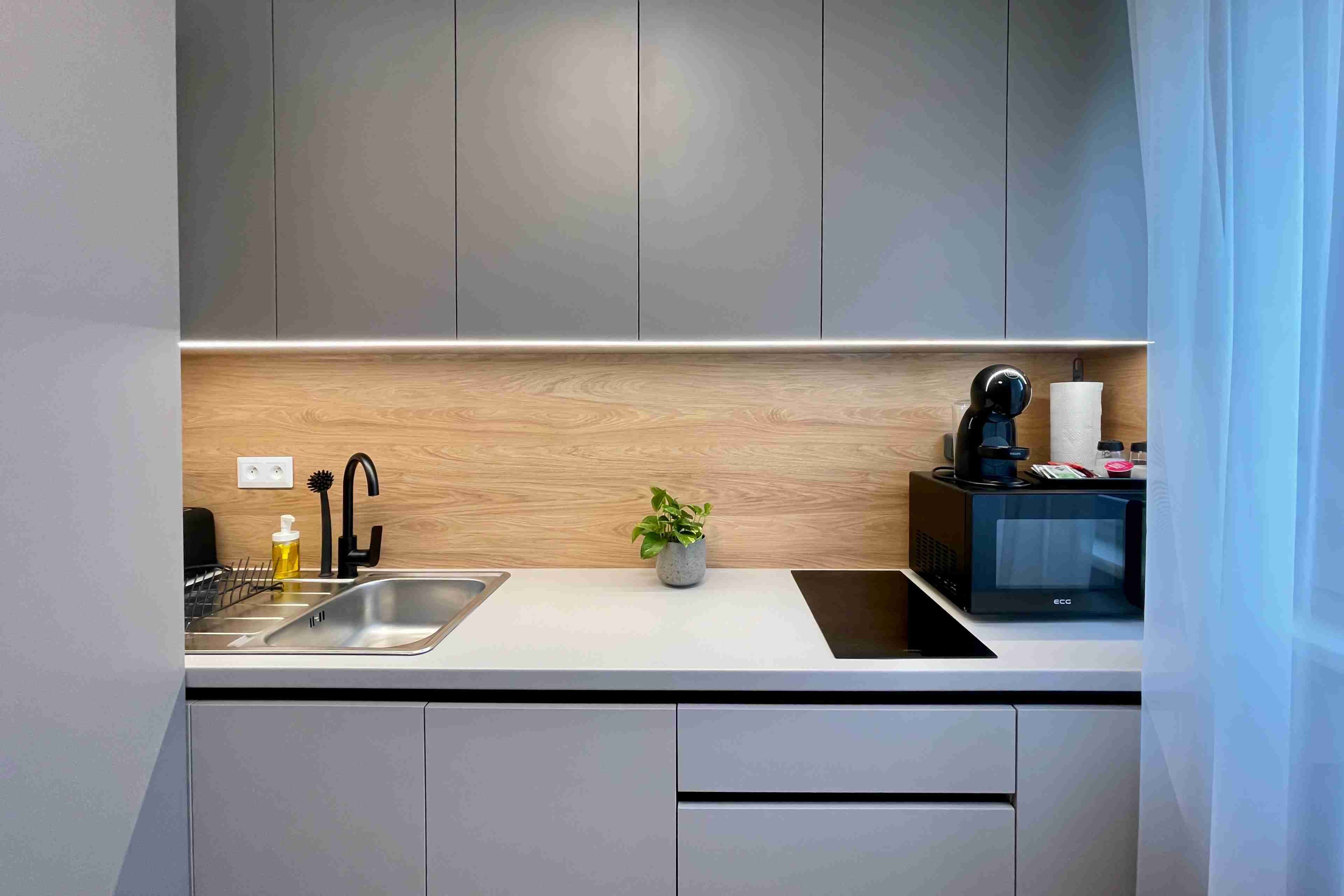 A modern kitchen with a stainless steel sink, a black coffee machine, and a microwave on the countertop.