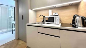 Una cocina moderna con microondas, hervidor y lavabo.
