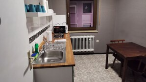 Een kleine keuken met een spoelbak, aanrecht en een raam.