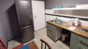 Een kleine keuken met een koelkast, gootsteen en een klein aanrecht.