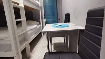Ein Stockbett mit Schreibtisch und Stuhl in einem Zimmer mit gemustertem Teppich.