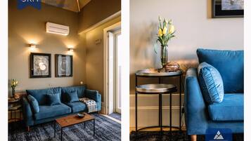 A modern living room with a blue sofa, a coffee table, and a round side table with a vase of flowers.
