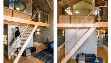 Ein modernes Loft mit einer Holztreppe, einer kleinen Sitzecke und einer Küchenzeile.