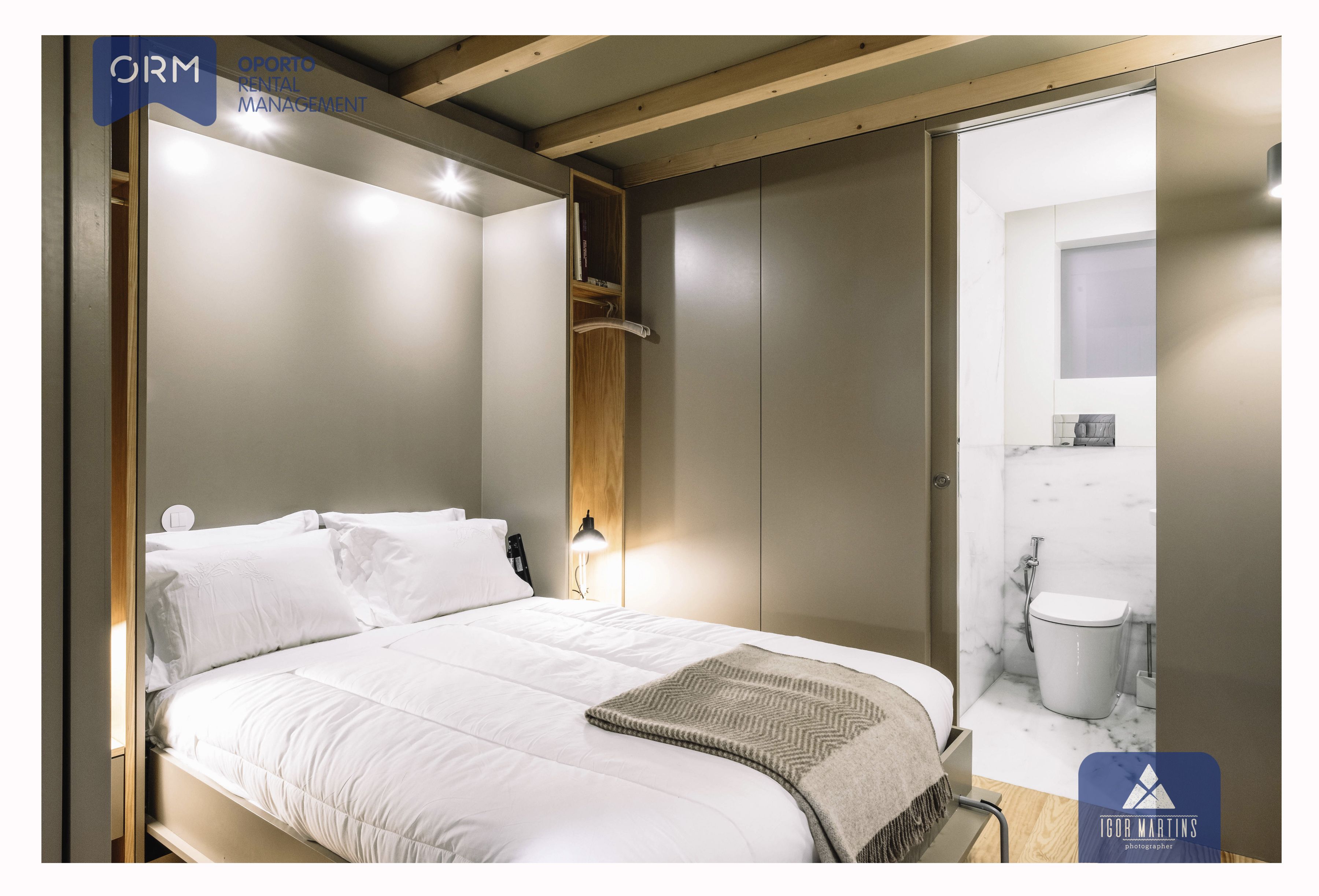 A modern bedroom with a bed, bedside table, and a wardrobe.