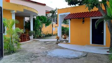 Un patio con un edificio amarillo, una reja negra y plantas en macetas.