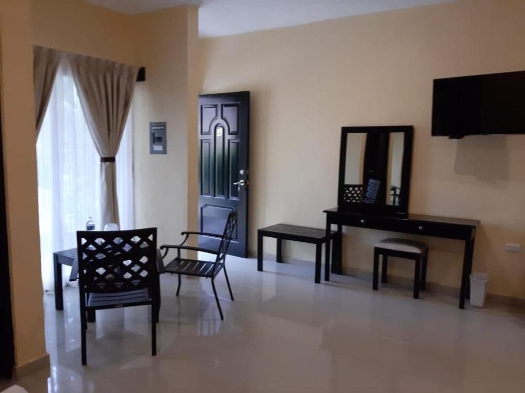 A room with a desk, two chairs, a mirror, and a television.