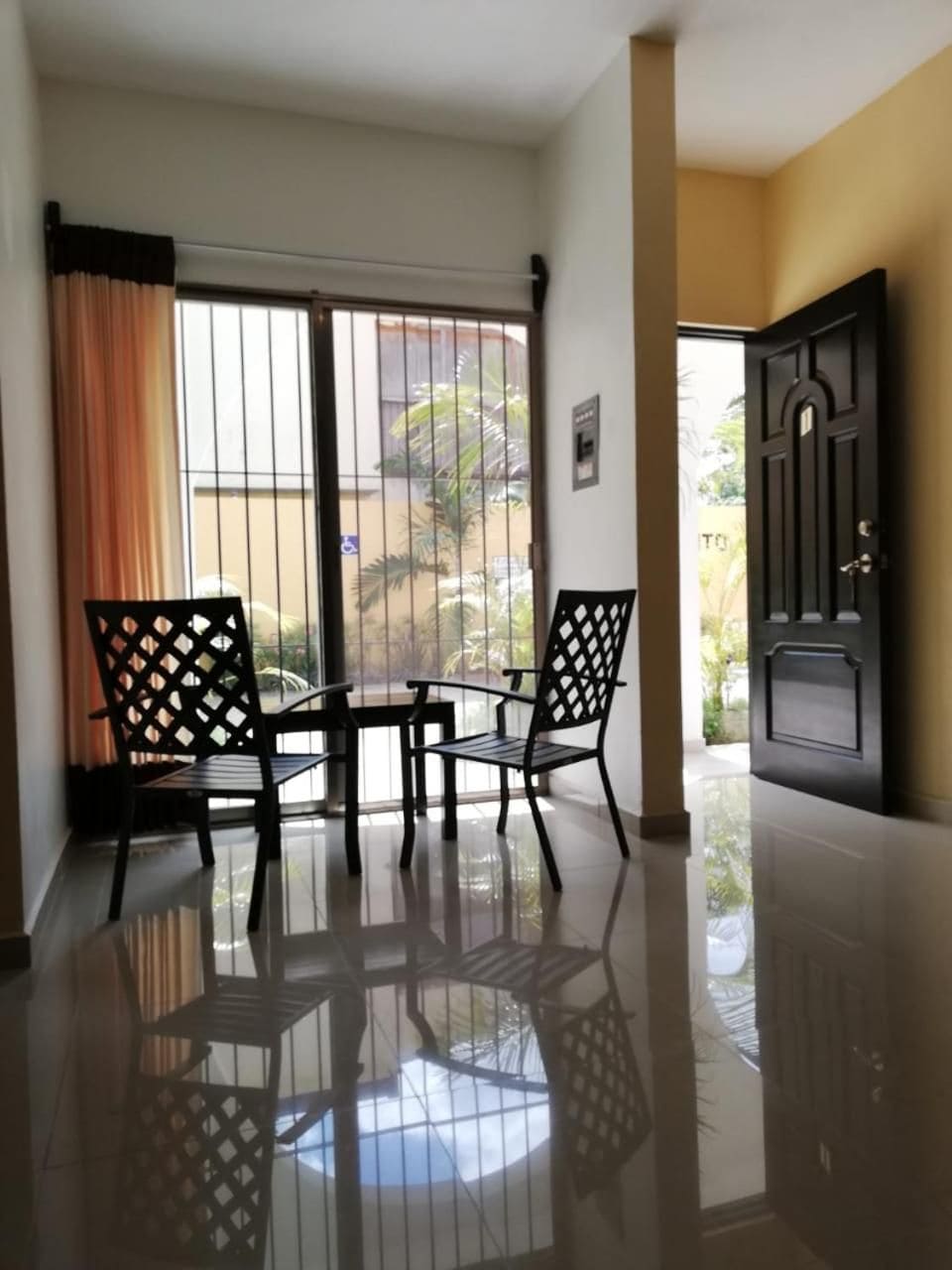 Una habitación con balcón, una mesa, dos sillas y una puerta.